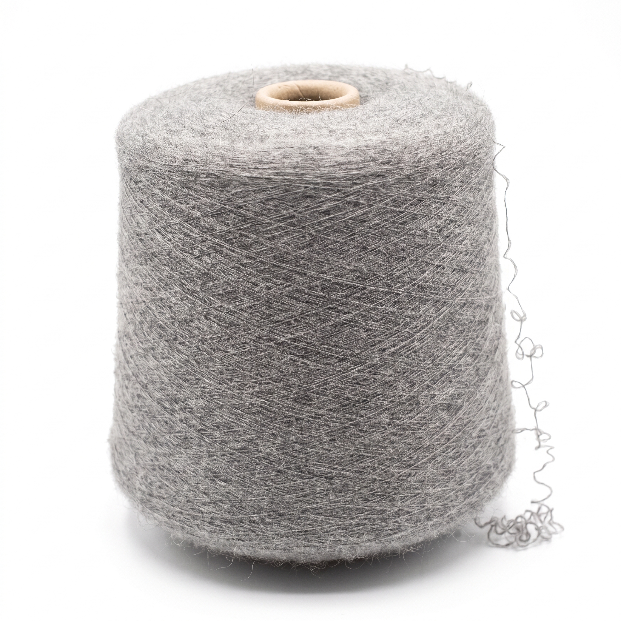 En stor cone med gråt, fibret garn og en løs, krøllet tråd på en hvid baggrund.