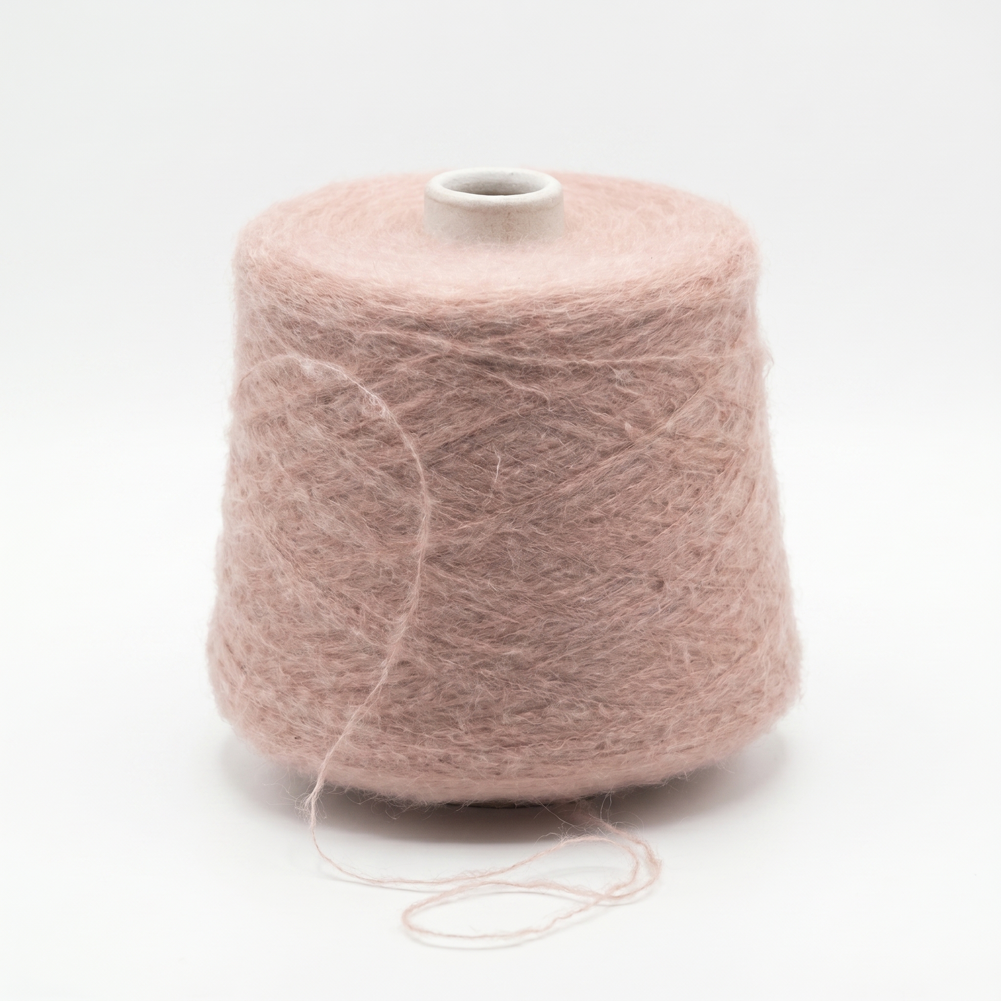 En cone med støvet rosa, loddent garn står på en hvid baggrund.