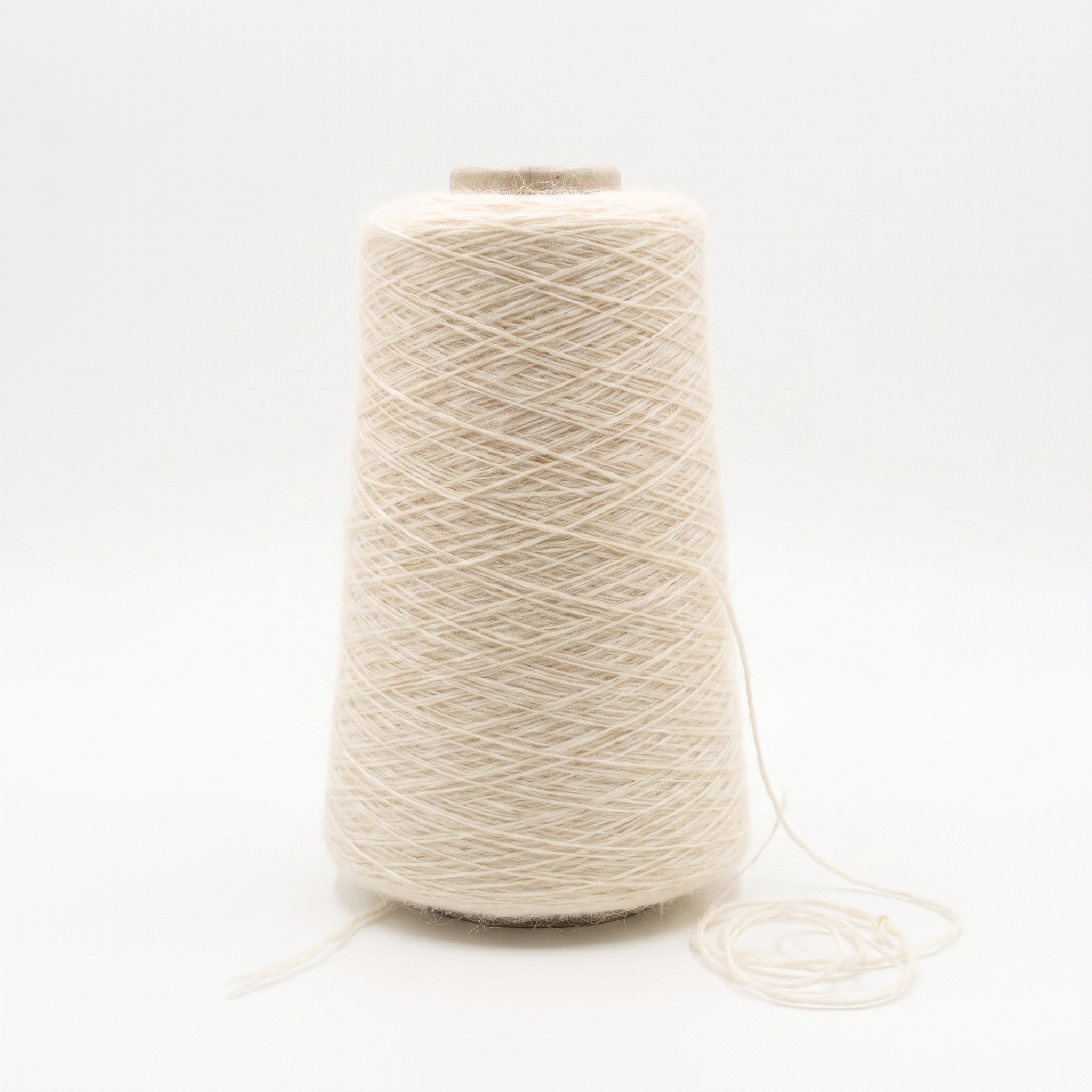 En cone med lyst beige, uldent garn og en løs tråd ved bunden.