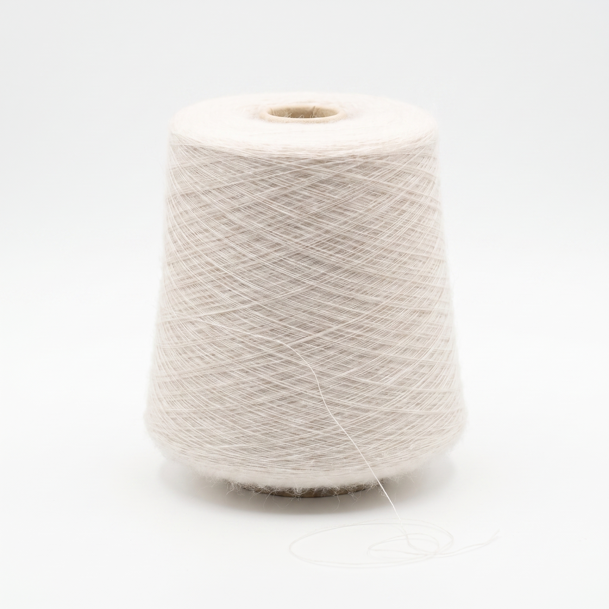 En cone med fint, lyst beige garn på en hvid baggrund.