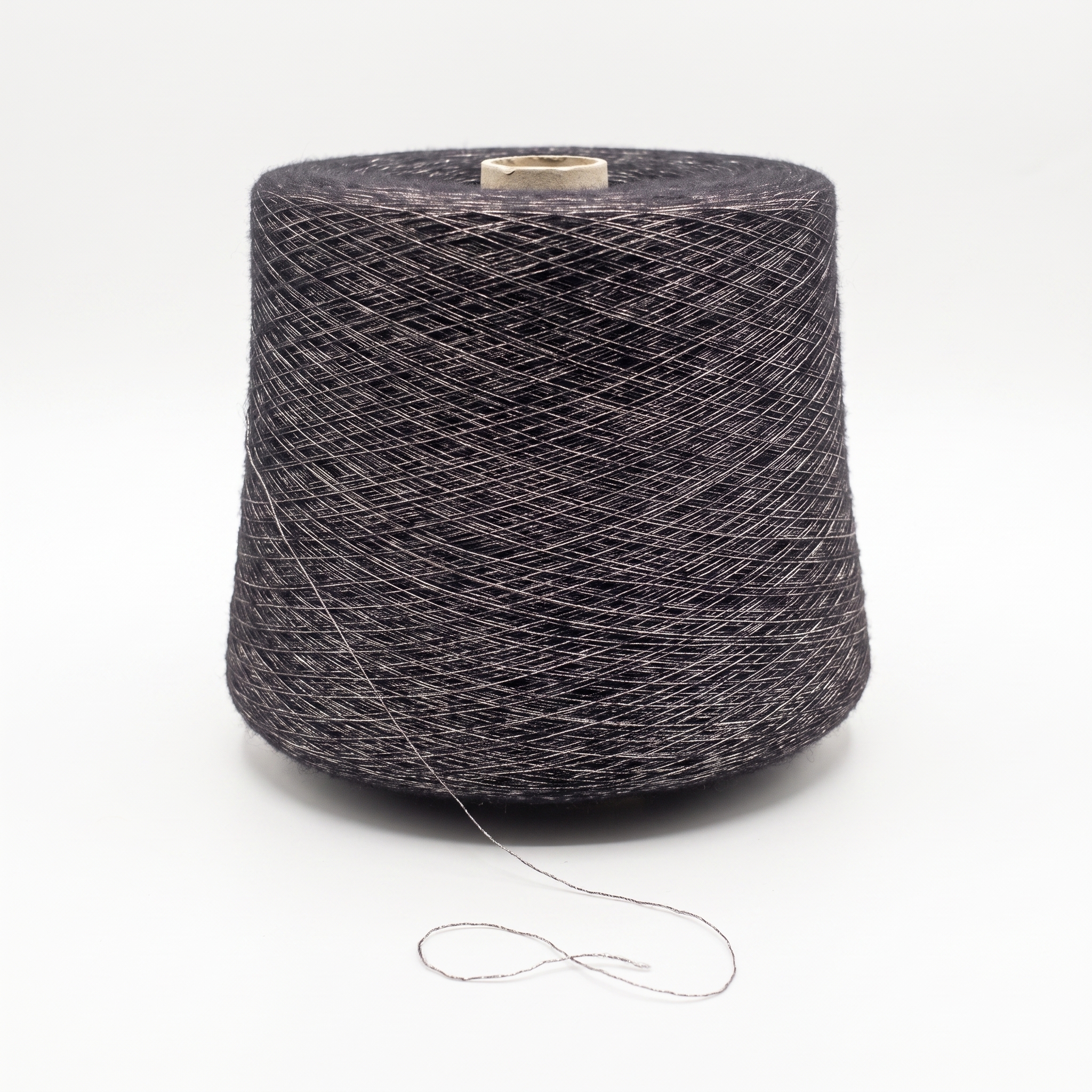 En stor cone med mørkegråt garn og en sølvfarvet glittertråd, stående på en hvid overflade.