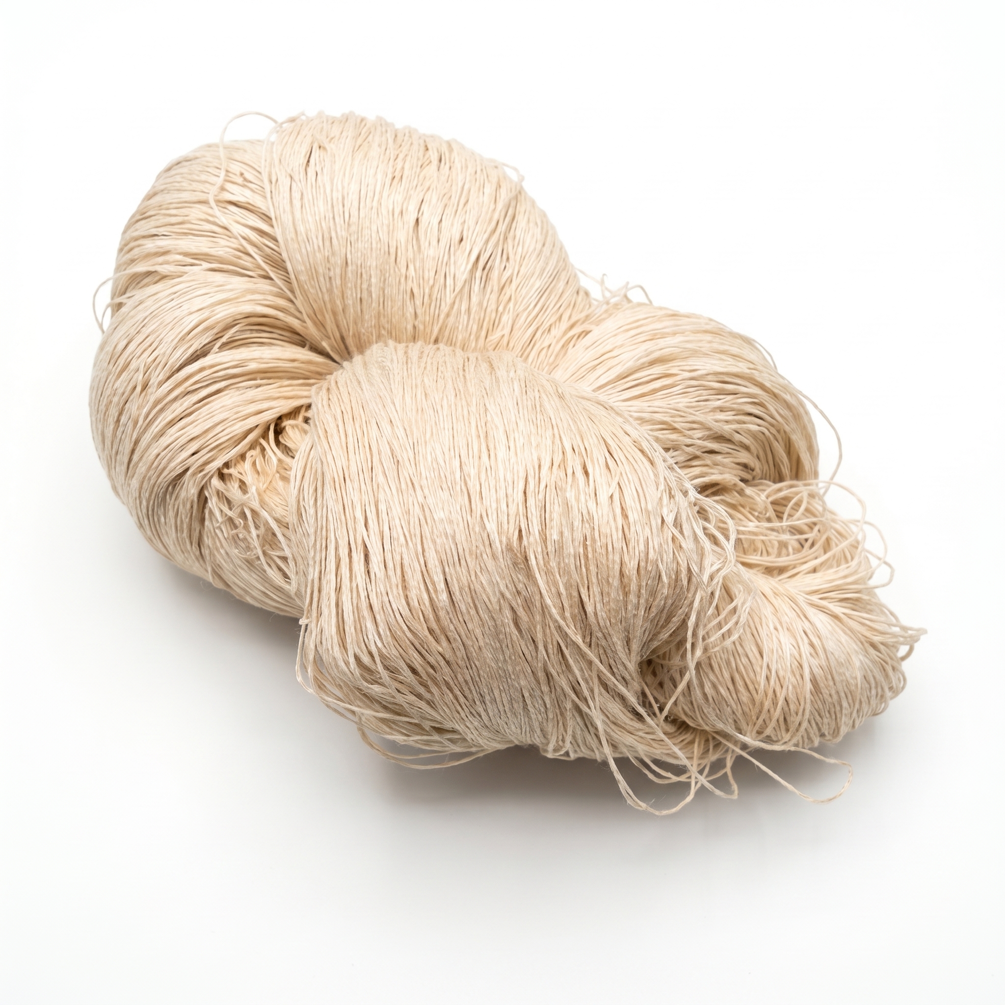 En stor fed med lyst beige garn ligger på en hvid overflade.