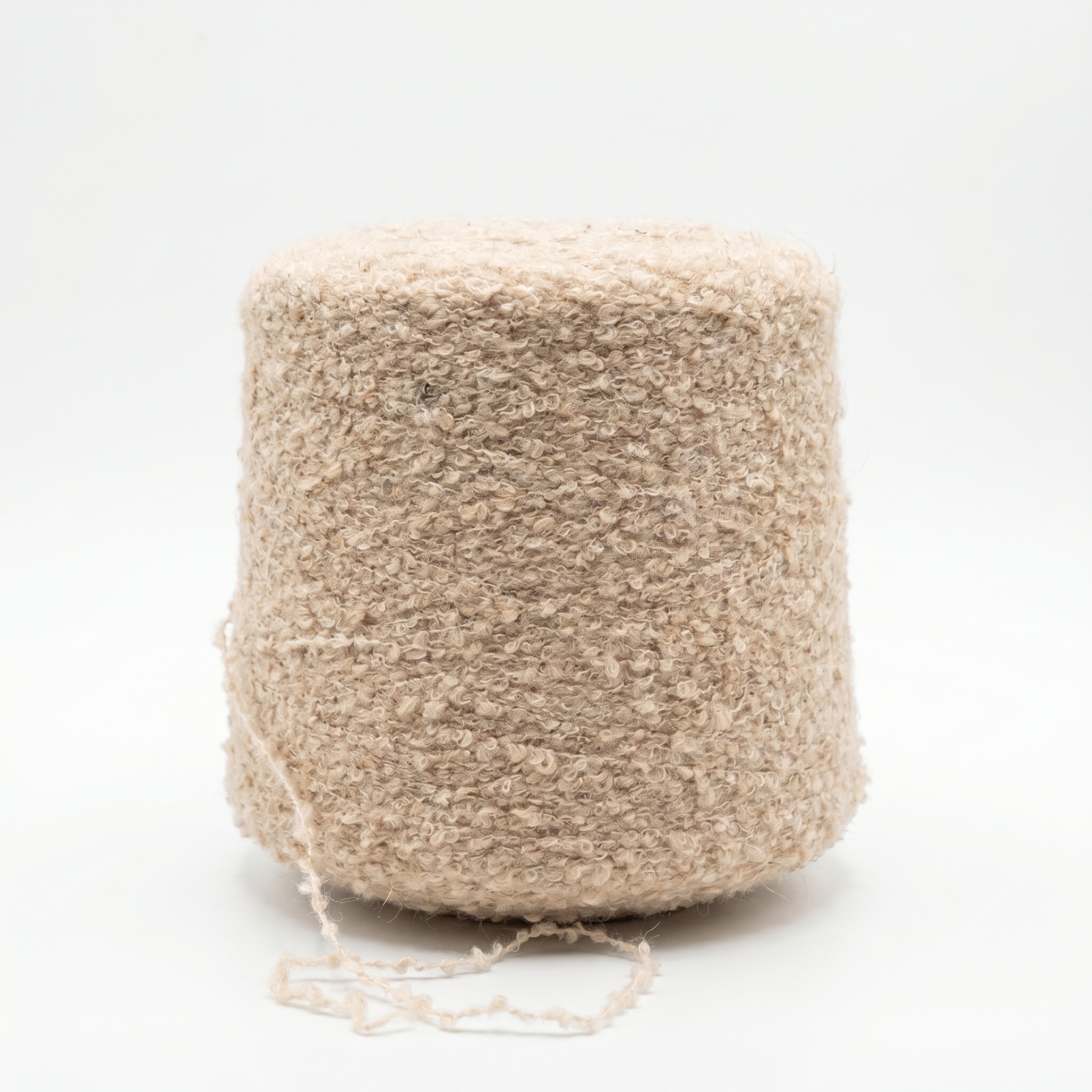 Et billede af beige, tekstureret garn viklet på en stor cone, med en løs tråd i bunden mod en hvid baggrund.