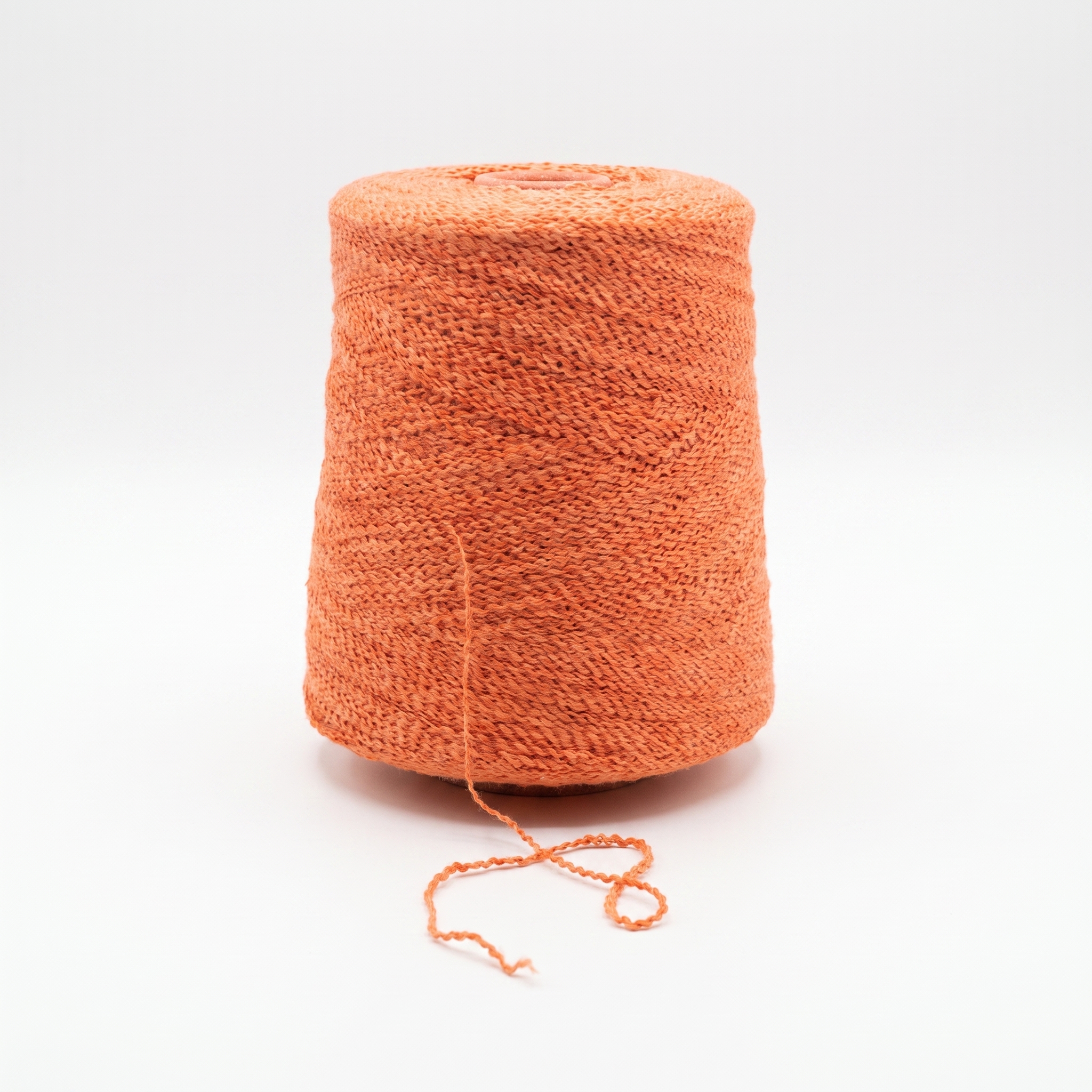 En cone med orange, tekstureret garn på en hvid baggrund.