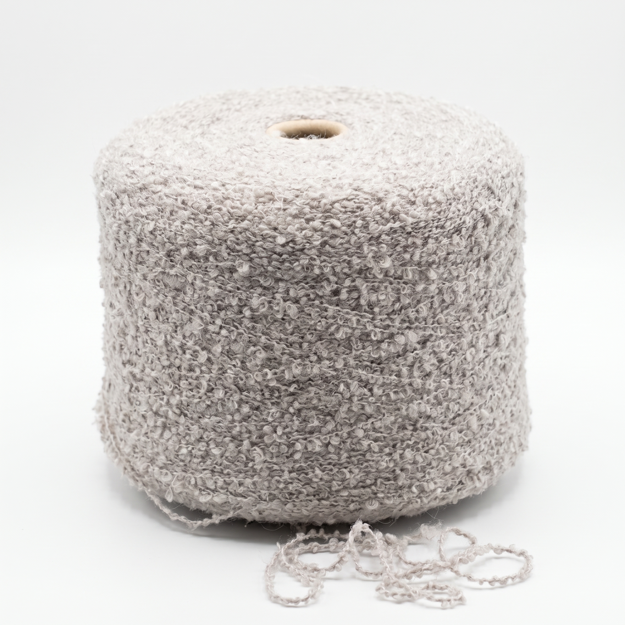 En stor cone med beige bouclé-garn og en smule garn ved foden.