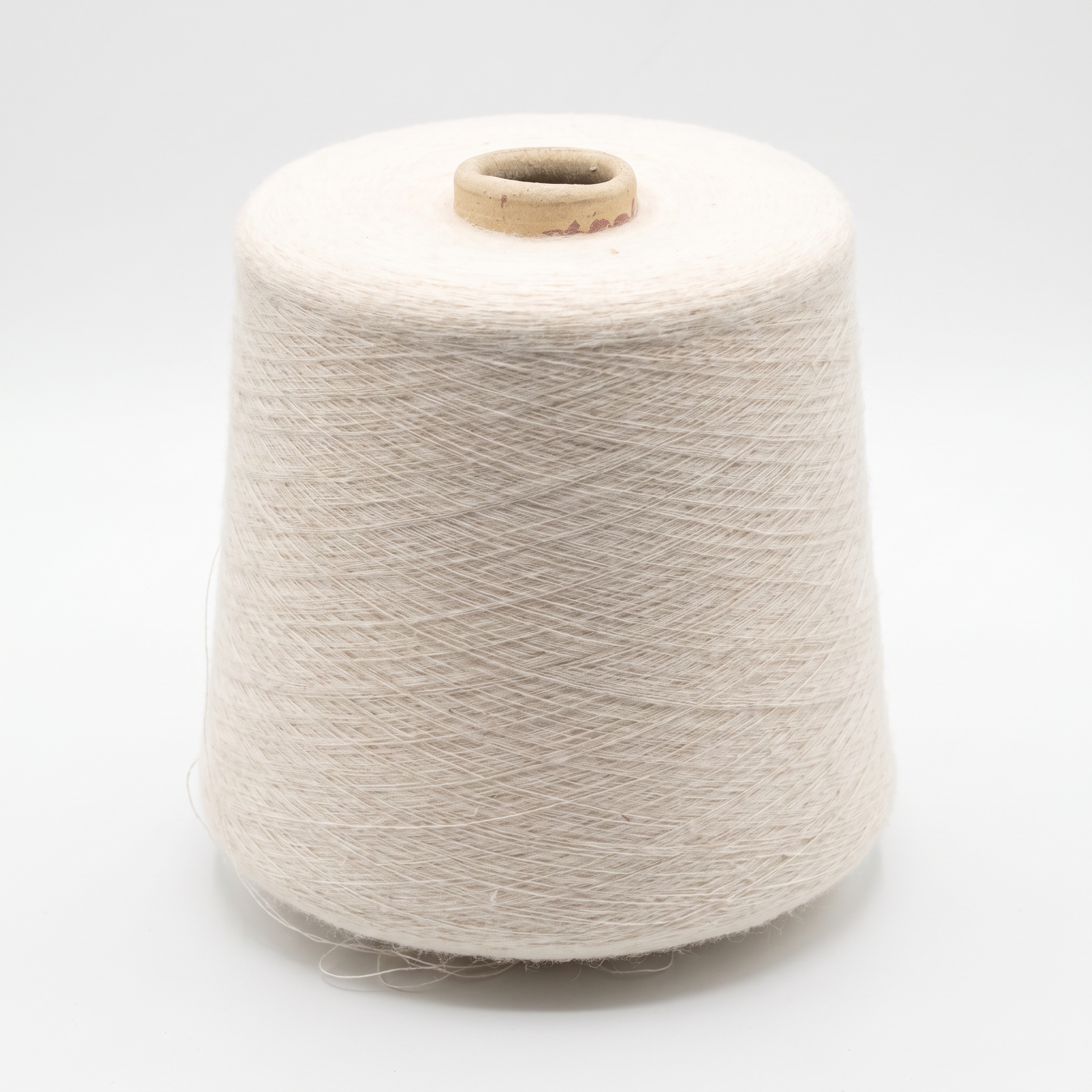 En cone med lyst beige garn på en hvid baggrund.