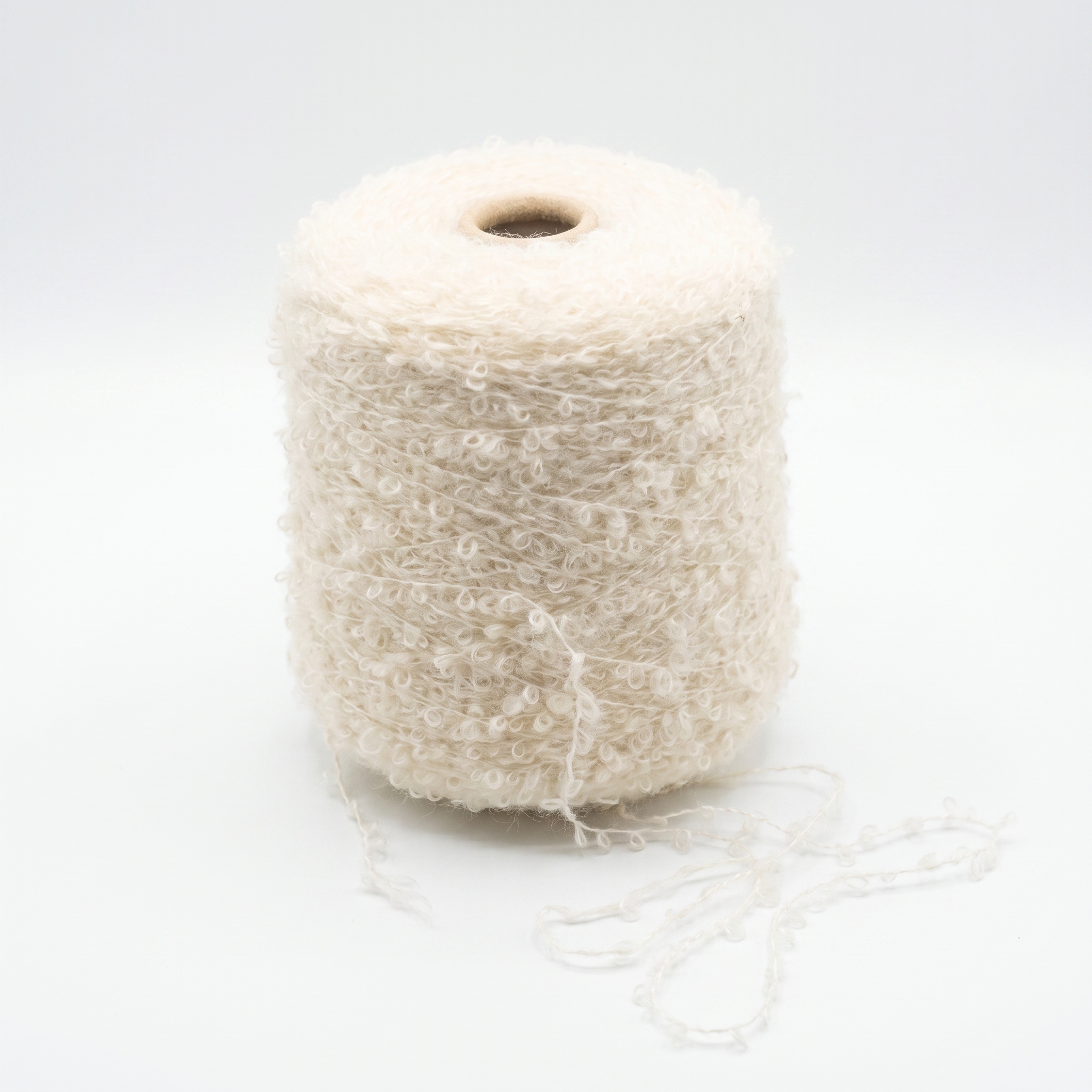 En cone med naturhvidt bouclégarn med lidt løst garn ved bunden mod en hvid baggrund.
