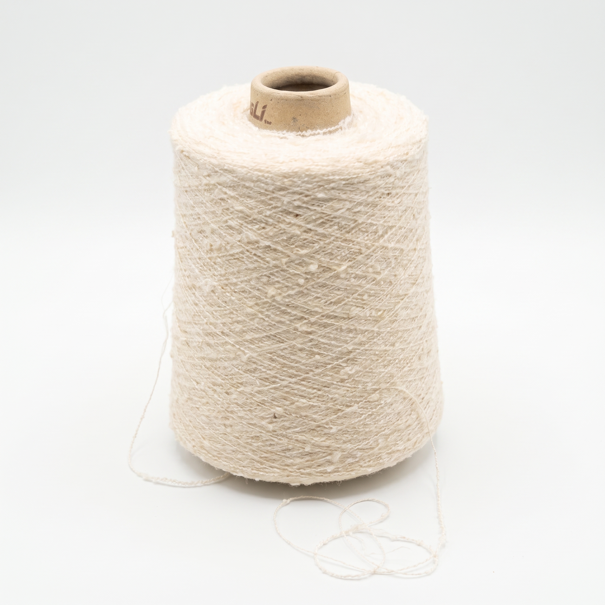 En stor cone med tekstureret, cremefarvet garn og en løs tråd ved bunden på en hvid baggrund.