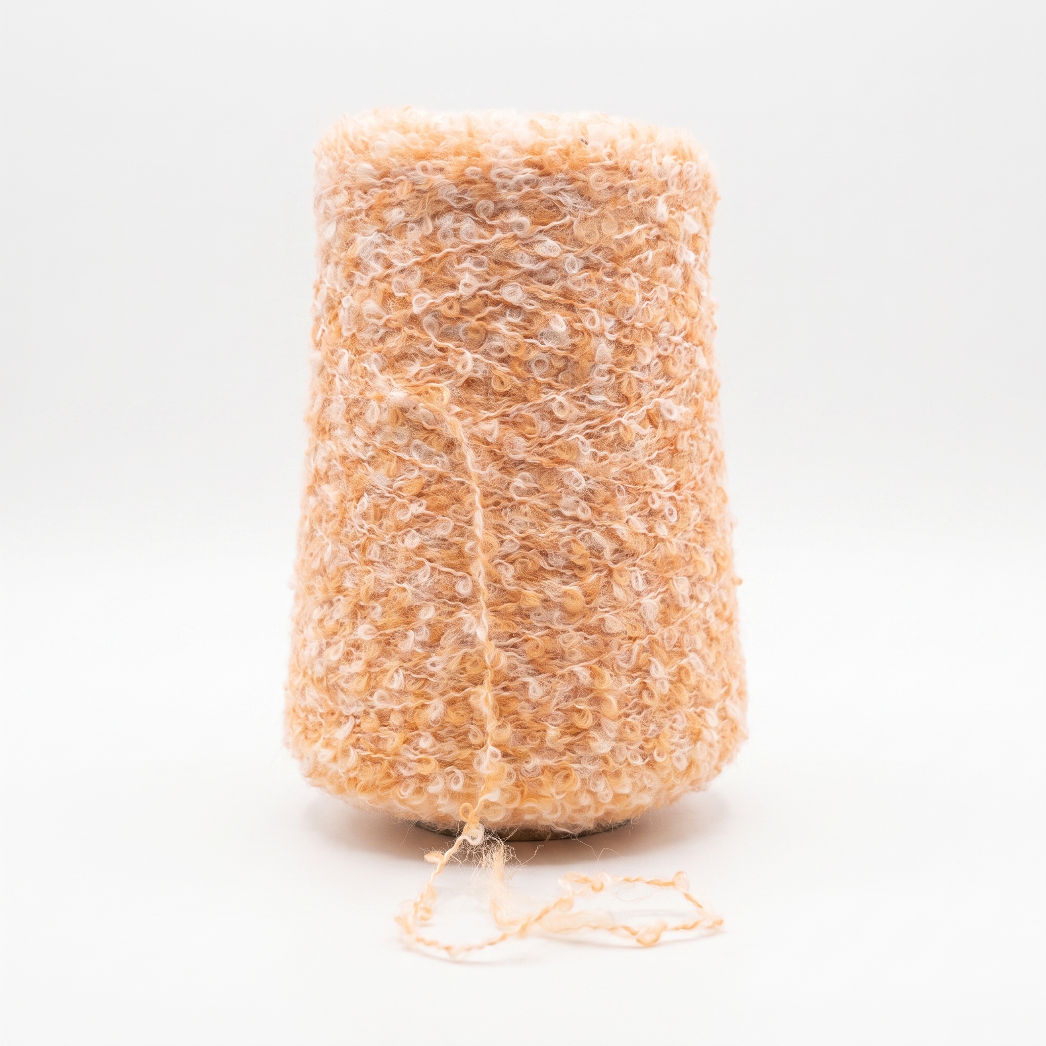 En cone med løkkegarn i en blanding af orange og hvid farve, med en løs tråd forneden.