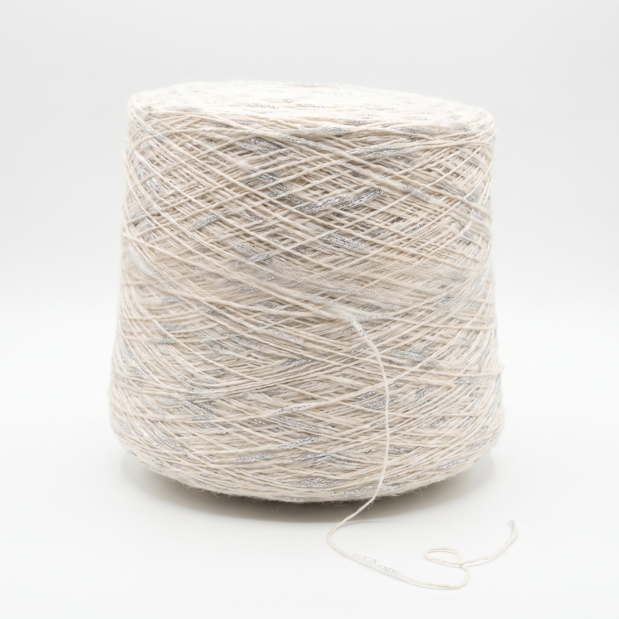 En stor cone med lyst beige garn og sølvglimmertråde, på en hvid baggrund.