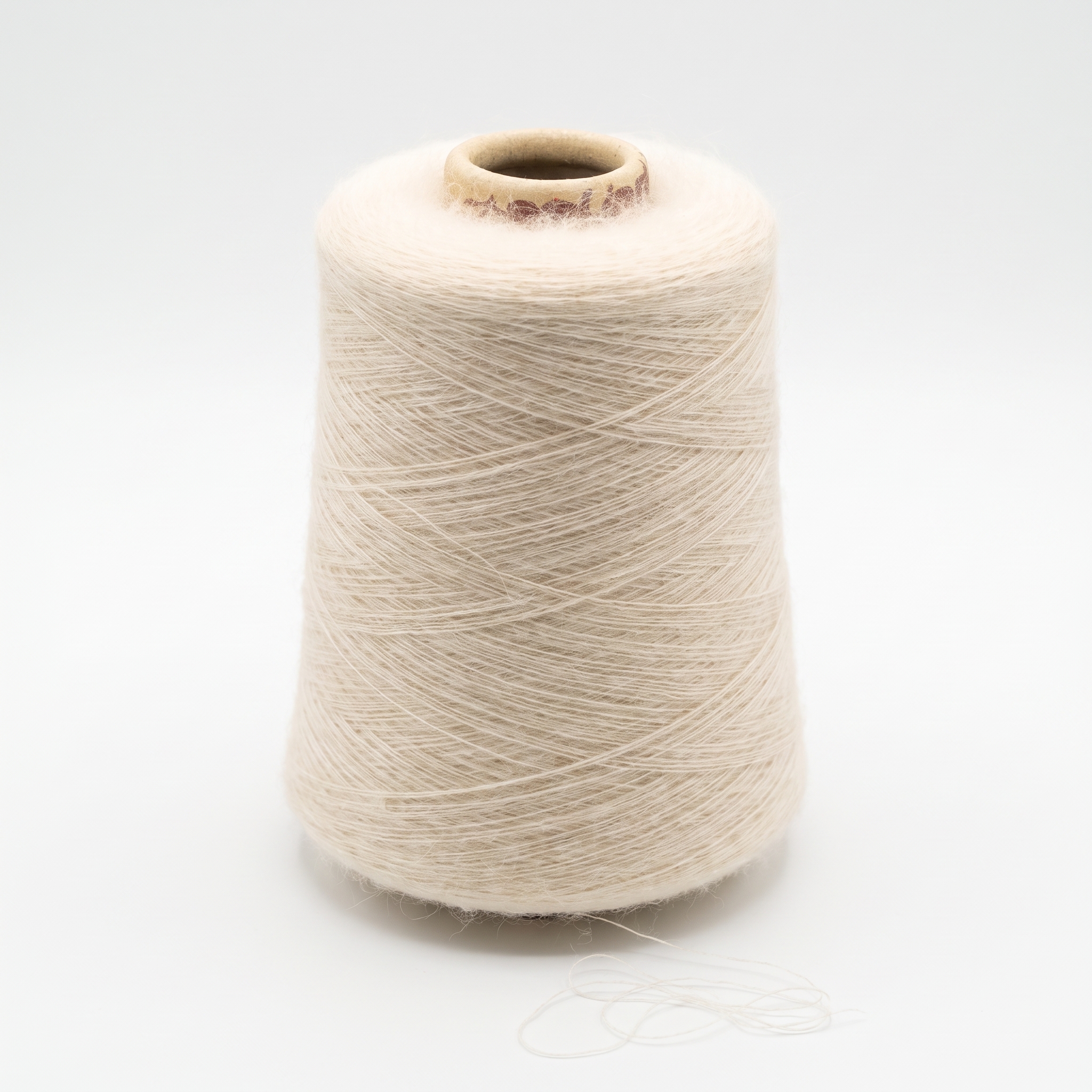 En cone med lyst, fnugget garn vises på en hvid baggrund, med en løs tråd ved bunden.