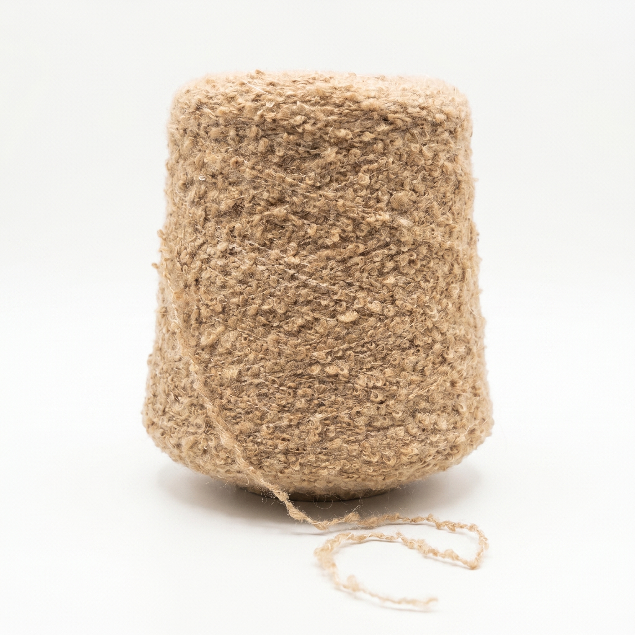 En stor cone med beige bouclégarn mod en hvid baggrund.