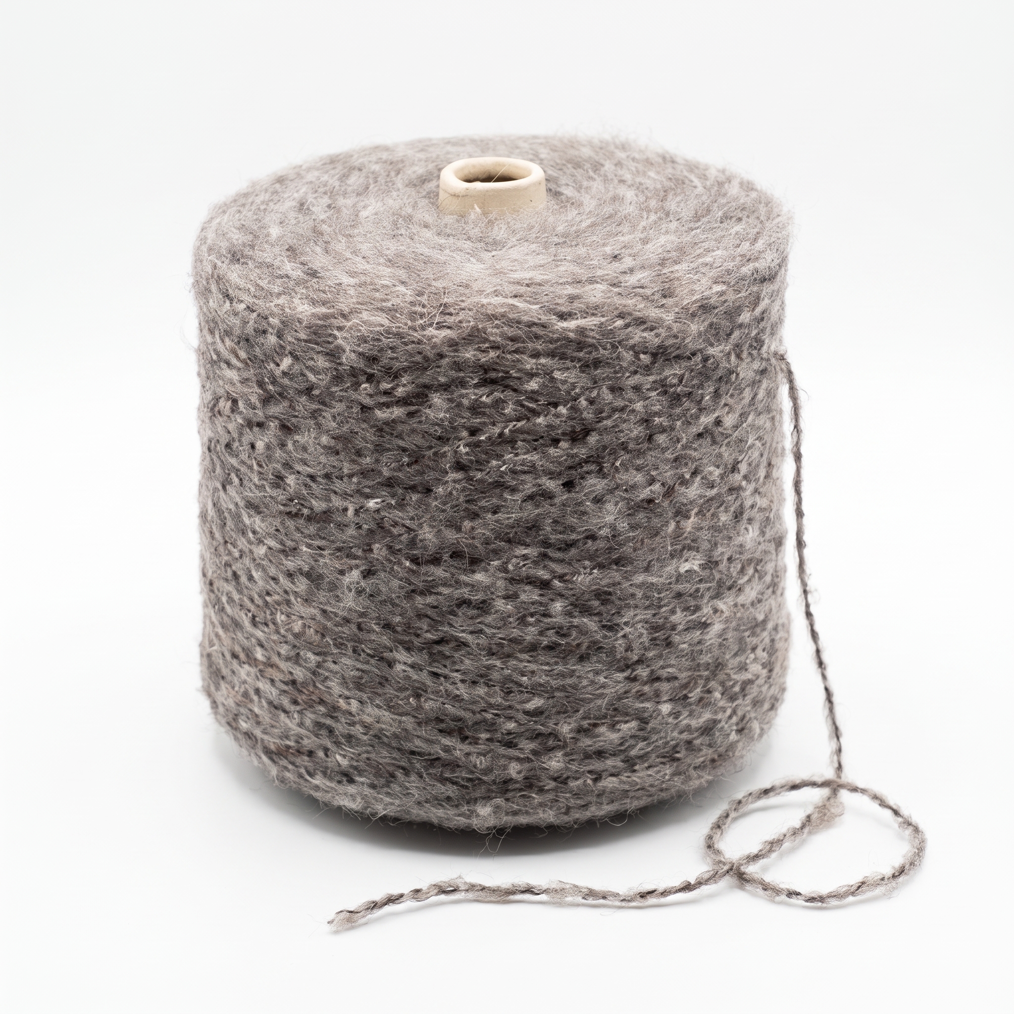 En stor cone med struktureret, gråbrun garn og en løs tråd på en hvid baggrund.